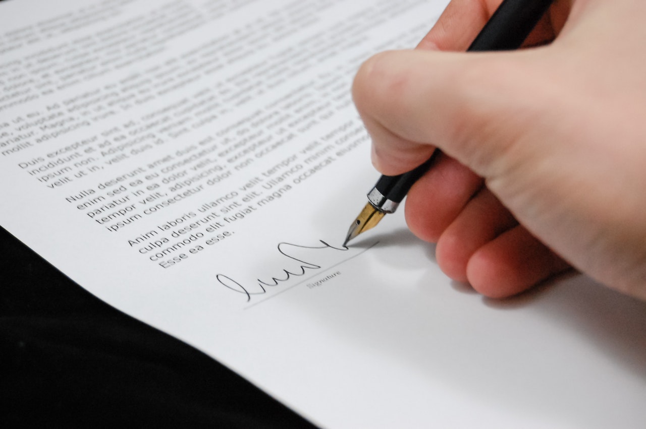 One person signing a legal document with a fountain pen.
